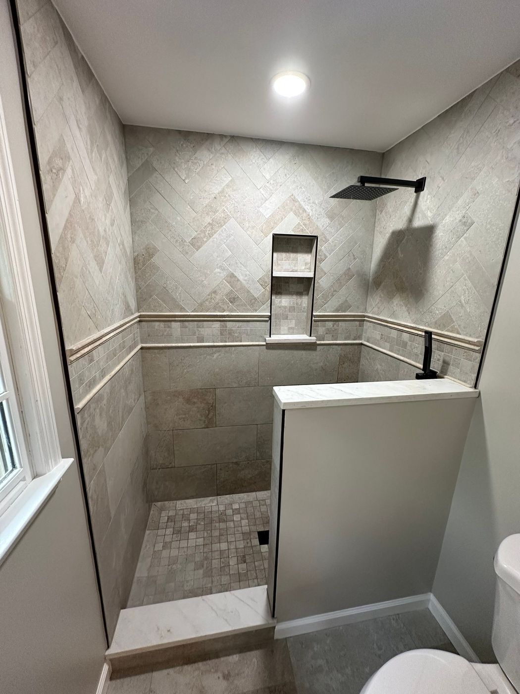 A finished Adams Tile shower with herringbone tile