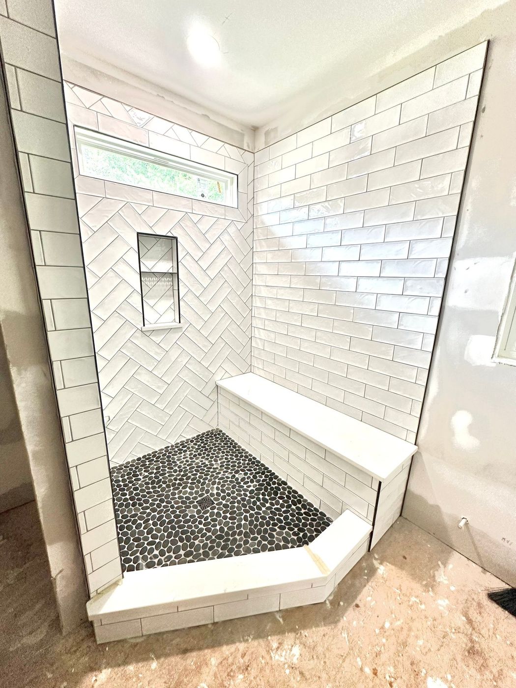 Herringbone accent, pebble floor and a tiled bench