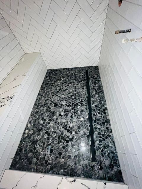 Herringbone walls, pebble floor and a linear drain