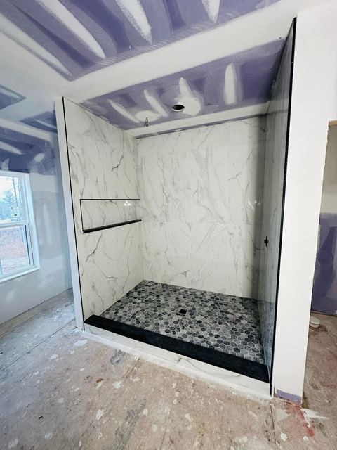 Marble-look shower on a pebble floor