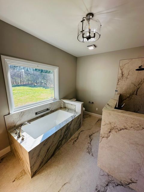 Marble-look tub deck under a picture window
